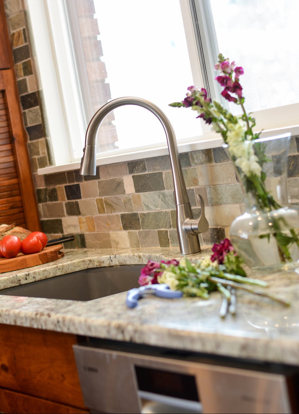 Kitchen sink with slate backsplash and cut flowers