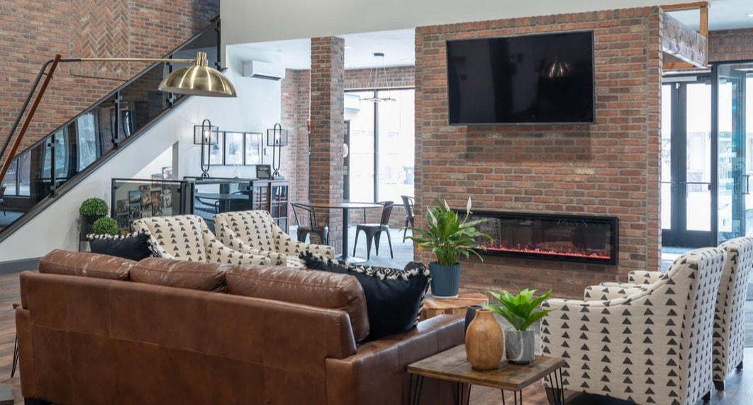 Industrial contemporary office waiting room with large leather sofa and fireplace