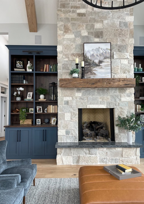 Stone fireplace with blue built in cabinets and large leather ottoman